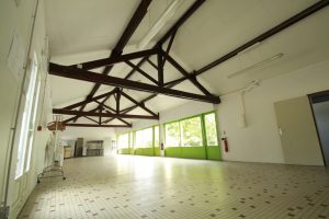 La salle B du Clos de Soucelles, ses poutres rustiques et sa série de baies vitrées ouvertes sur le parc